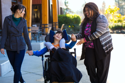 two woman guiding a boy on wheelchair